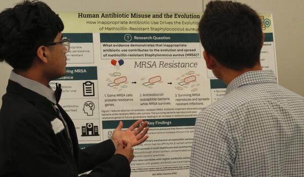 Student sharing information on his poster with others.