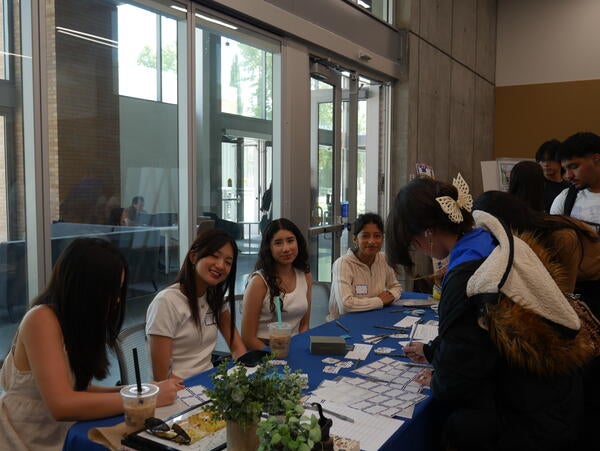 Students assisting with sign ins and promoting community achievements (with boba)