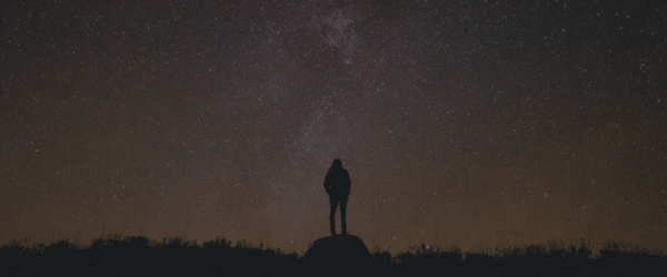 An image of the milky way from a dark zone with a lone figure searching the stars